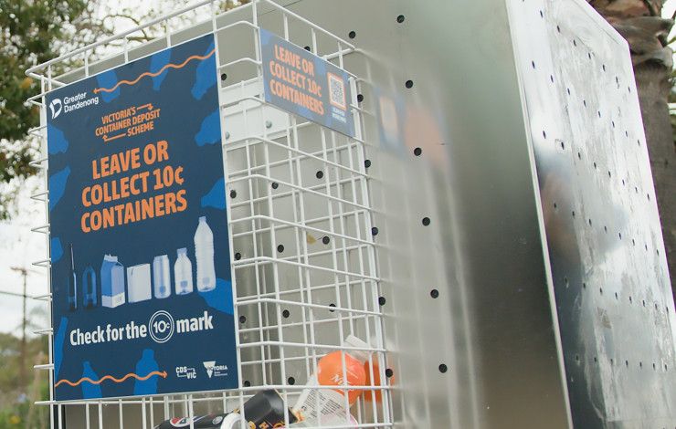 A small cage attached to the side of a stainless steel rubbish bin with a sign that reads “Leave or collect 10 cent containers”.