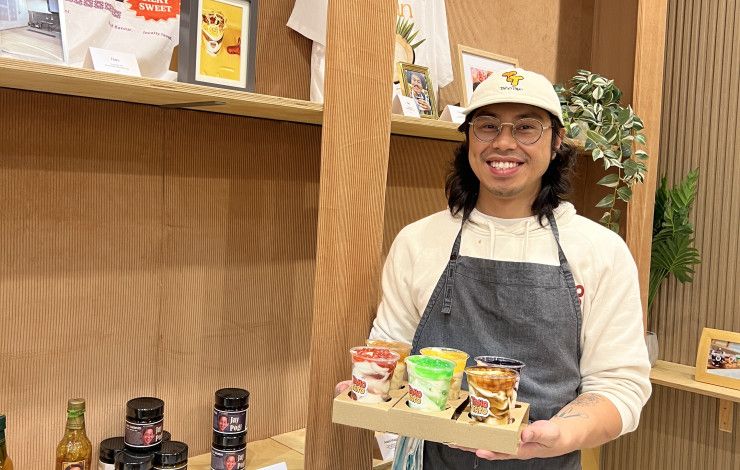 A smiling man holds a tray of sweet treats