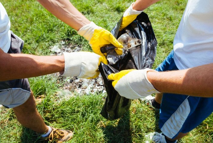 Two people putting litter into bag