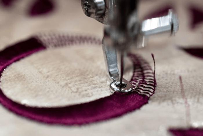 embroidery machine sewing a letter with burgundy thread