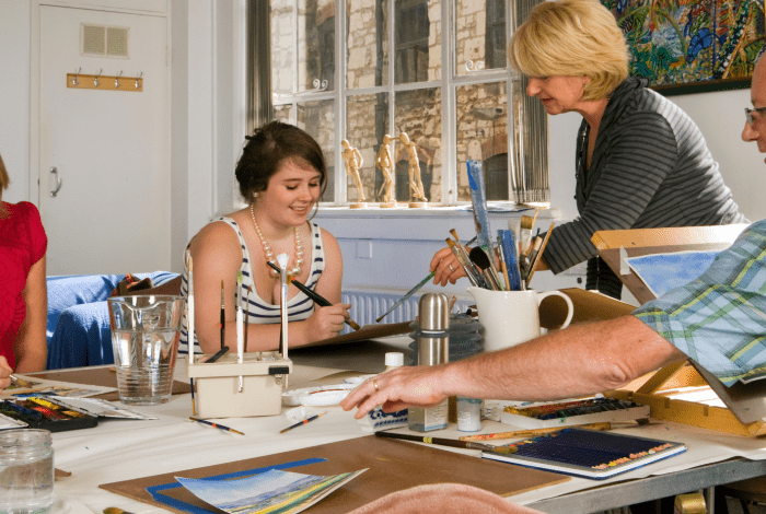 Art class with four people painting on paper.