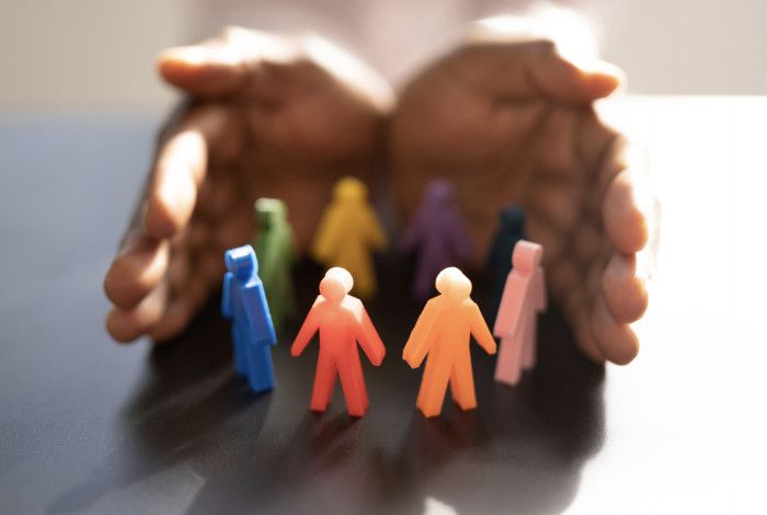 Colorful figures of humans being cupped by two hands.