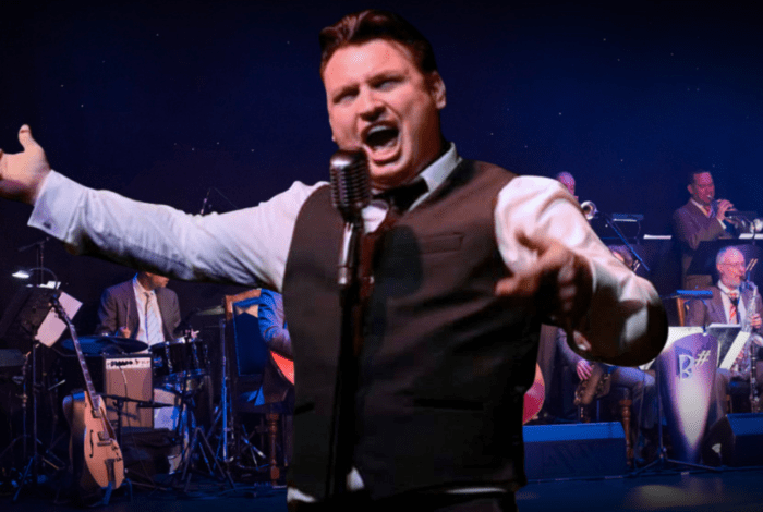 Person singing passionately in from of big band