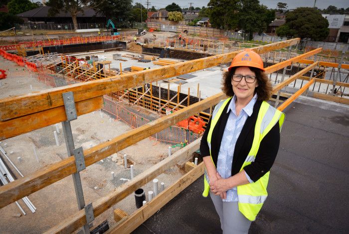 A woman dressed in a high vis vest and a hard hat stands on a platform overlooking a worksite