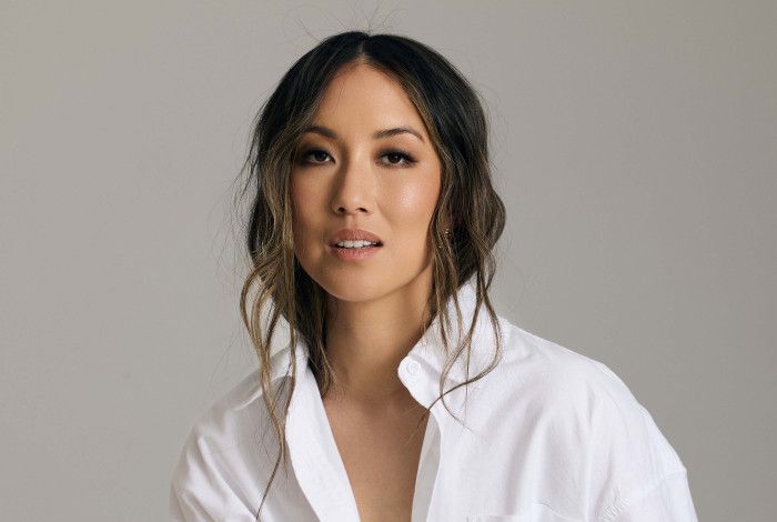 A smiling woman posing in a white shirt and black pants