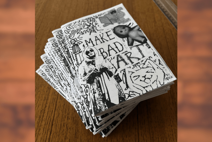 A wooden table with a stack of Zines on it. 