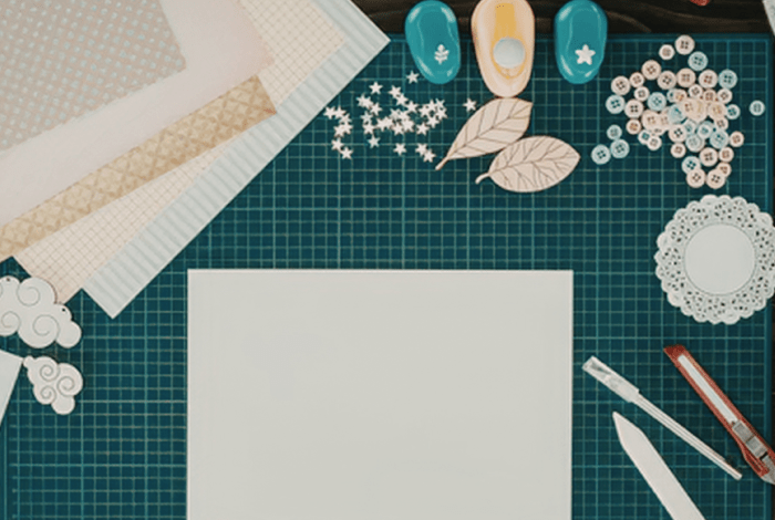A cutting mat covered in paper, stencils and tools used to make cards. 