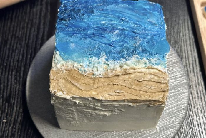 A cake decorated to look like a beach on a silver platter. 