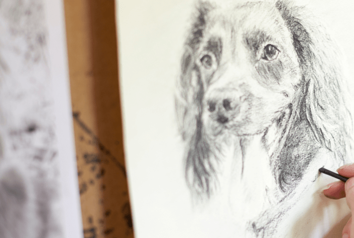 A person drawing a dog on paper.