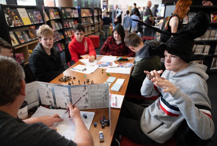 Group of young people playing dungeons and dragons around a table.