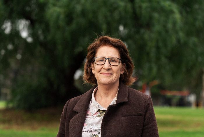 A smiling woman stands in a park.