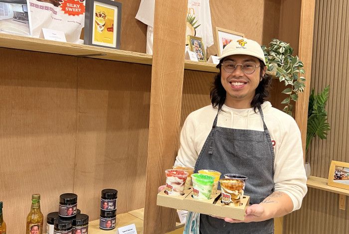 A smiling man holds a tray of sweet treats