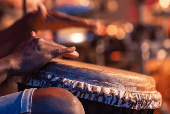An African musician playing the traditional drums against a colourful background.