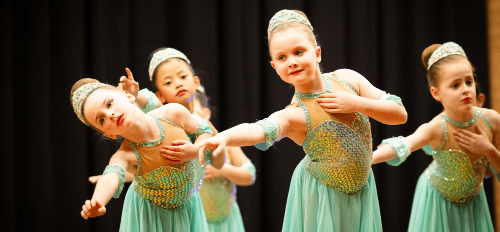 Children in sparkly costumes performing a calisthenics dance on stage