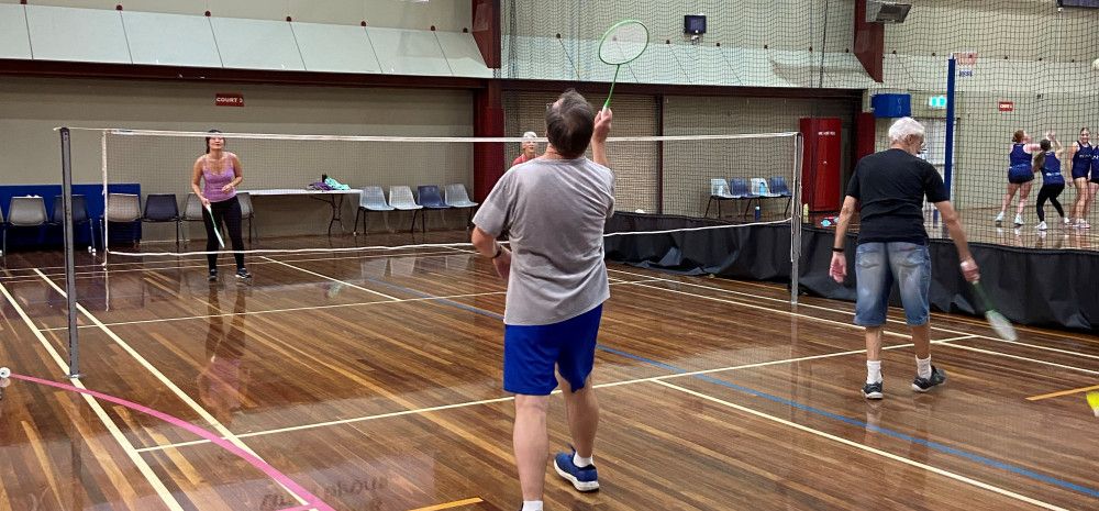 People playing badminton on an indoor court