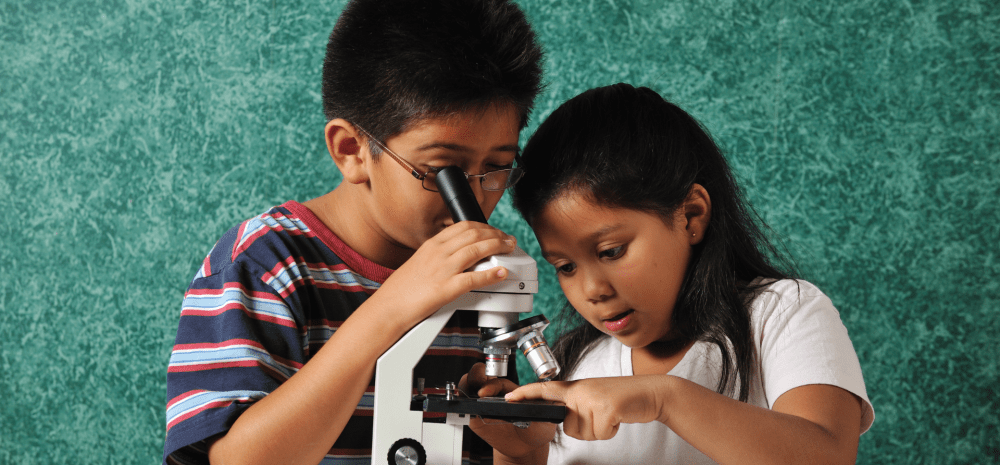 two children looking into a microscope