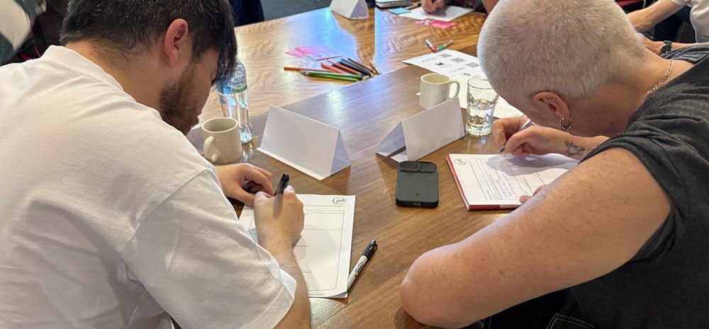 Two people writing at a workshop