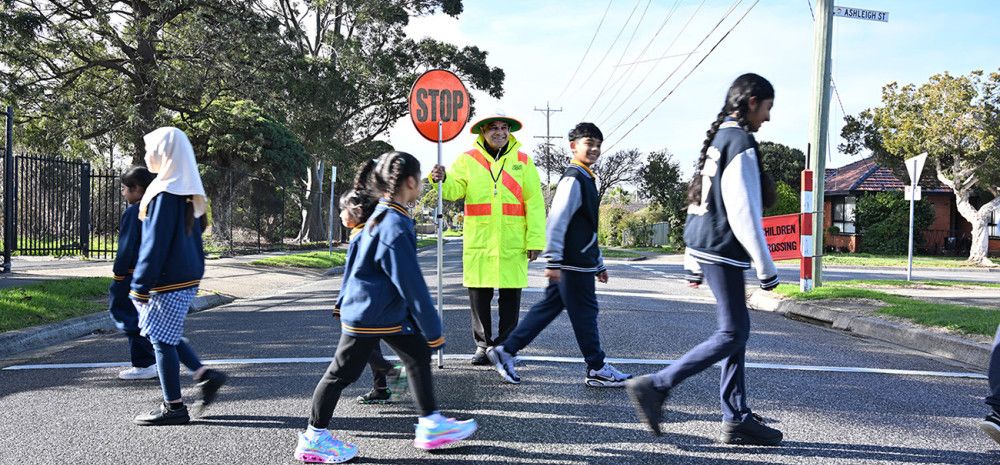 A man with a stop sign and children using a crossing