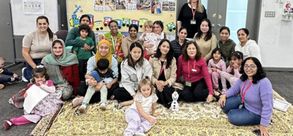 A large group of mums and their children smiling at the camera
