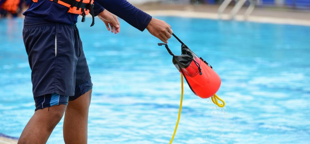 Lifeguard throwing rescuse equipment in water