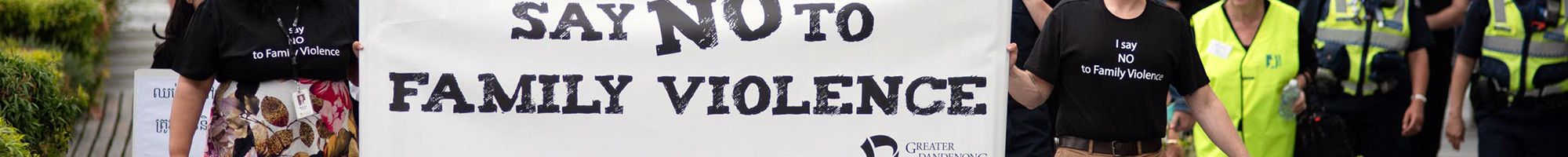 A large group marching with a sign saying 'We say no to family violence' 