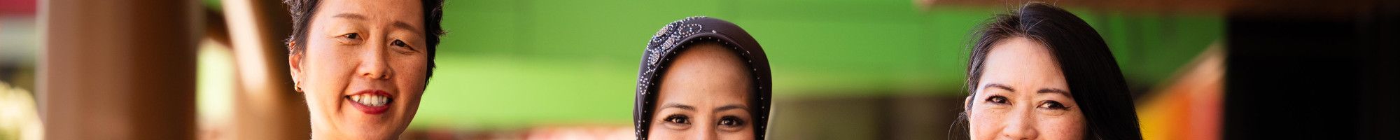Three women stand in a line and smile at the camera