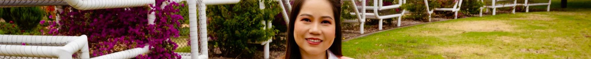 A woman dressed in a light pink blazer standing in front of a metal sculpture spelling out Springvale