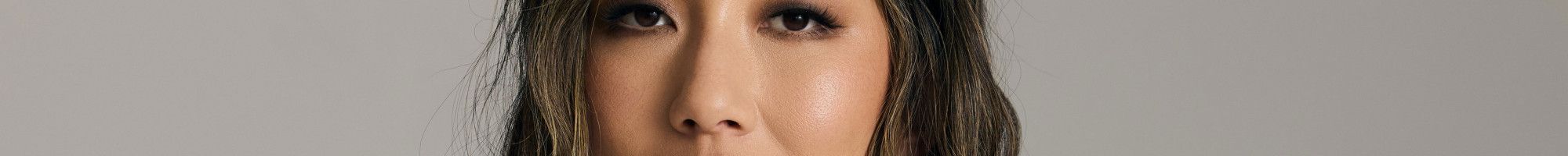 A smiling woman posing in a white shirt and black pants