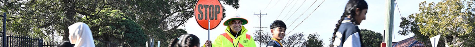 A man with a stop sign and children using a crossing