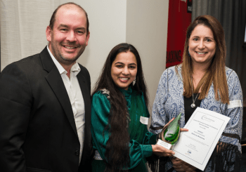 Three people with one holding an award and certificate