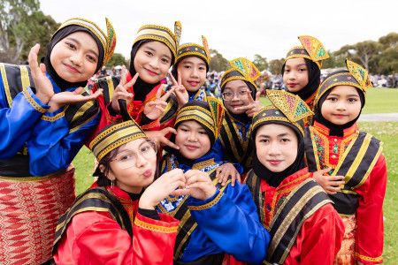 A group of smiling children wearing traditional Indonesian clothing