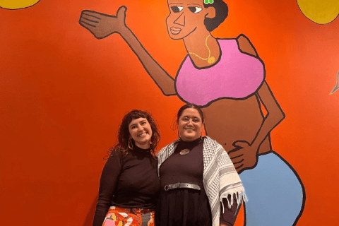 Two pwople stand in front of colourful mural