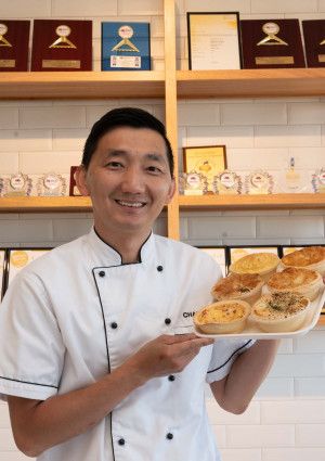 Man holding a tray of pies at his business